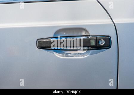 Zweiteiliger Kfz-Türgriff in glattem Metallic-Grau mit hochglänzend gestrecktem Kunststoffhauptteil und rechteckigem Schließmechanismus mit ke Stockfoto