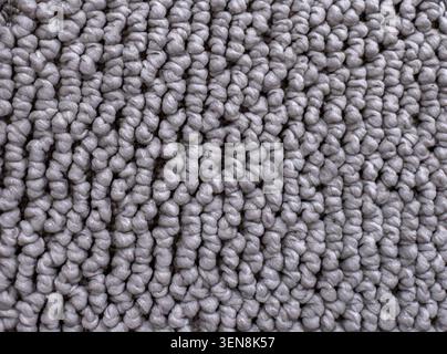 Nahaufnahme aus grauem gewebtem Teppich oder Textilgewebe mit detaillierter Schlaufenstruktur. Abstrakter Hintergrund mit weichen Fasern und kompliziertem Webmuster, s Stockfoto