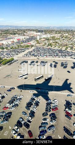 Die Boeing 737 MAX 9 wirft einen dramatischen Schatten über den Flughafenparkplatz, als sie schließlich den Los Angeles International Airport LAX mit der Skyline von Los Angeles erreicht Stockfoto