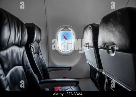 Innenraum der Flugzeugkabine, leere, komfortable Passagiersitze in der Economy Class mit Bullaugen. Stockfoto