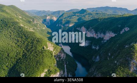 Luftpanorama des Drina River Canyon, der sich durch steile Bergtäler und üppige grüne Wälder schlängelt Stockfoto
