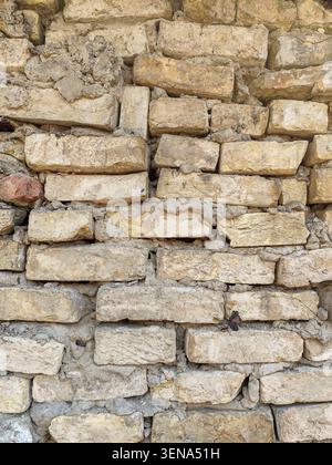 Alter verwitterter gelber Ziegelmauerhintergrund mit unordentlichem Zement Stockfoto