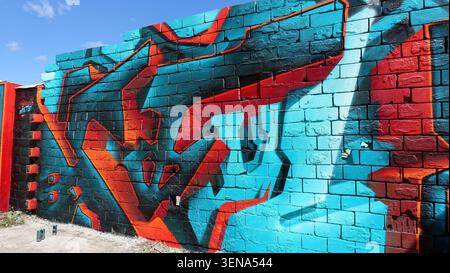 Stockholm, Schweden, 17. Mai 2026. Lebendiges blaues und rotes Graffiti-Wandgemälde über eine alte Ziegelwand mit auffälligen abstrakten Formen und dynamischem spr Stockfoto