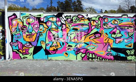 Stockholm, Schweden, 17. Mai 2026. Lebendiges abstraktes Graffiti-Wandgemälde mit verzerrten Gesichtern und mehreren Augen auf einer Betonwand im Freien Stockfoto