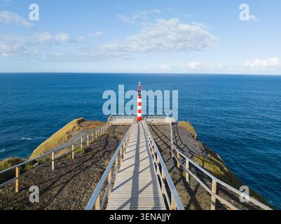 Kleiner Leuchtturm auf der zerklüfteten Klippe der Azoren, Sao Miguel, Schiffsanzeige, vulkanisches Gestein, Drohnenvideo Stockfoto