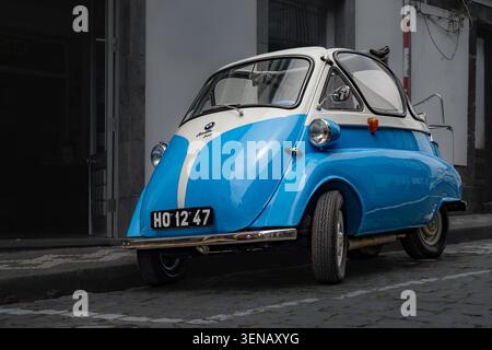 Ein Vintage-BMW Isetta-Mikroauto mit seiner einzigartigen, von vorne zu öffnenden Tür und der vollständig geöffneten Windschutzscheibe, die das klassische Retro-Design des Automobilbaus verkörpert Stockfoto