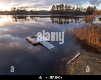 Frostbedeckter Badesteg am ruhigen Dubuļkas-See während des Winteruntergangs in Latgale, Lettland Stockfoto
