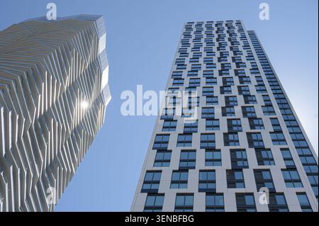 Flacher Blick auf zwei moderne Wolkenkratzer mit geometrischen Fassaden und reflektierender Glasarchitektur. Stockfoto
