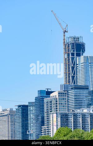 Moderne Skyline mit einem im Bau befindlichen Hochhaus über Wohn- und Geschäftsgebäuden. Stockfoto