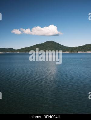 Ruhiges Wasser des Advancetown Lake am Hinze Dam an der Gold Coast, Queensland, Australien, reflektiert eine einsame Wolke und umliegende Hügel. Stockfoto