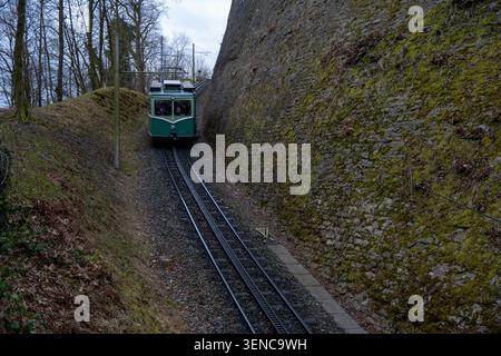 Königswinter, Deutschland - 22. Februar 25: Grüne Drachenfelsbahn auf der Hangstrecke und Steinschlag bei Schloss Drachenburg, Königswinter, Stockfoto