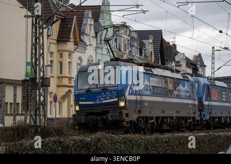 Königswinter, Deutschland - 22. Februar 25: Blaue elektrische Güterzuglokomotive, die durch eine Stadtbahn mit Freileitungen in Königswinter fährt Stockfoto