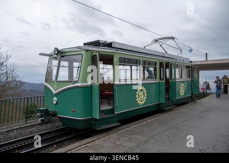 Königswinter, Deutschland - 22. Februar 25: Seitenansicht einer grünen Drachenfels-Bahn-Straßenbahn an einem Bahnsteig mit offener Tür in Königswinter, Nordrhein-Westfalen, Stockfoto