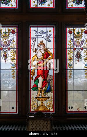 Königswinter, Deutschland - 22. Februar 25: Buntglasfenster mit allegorischer Figur und Pfau im Schloss Drachenburg in Königswinter, GE Stockfoto