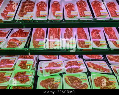 Frische, rohe Rindfleischstücke, verpackt in Tabletts, die an der Metzgerei im Supermarkt ausgestellt werden Stockfoto