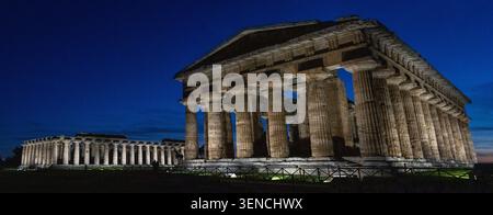 Großer Panoramablick auf beleuchtete antike griechische Tempel im archäologischen Park Paestum in Kampanien, Italien, fotografiert in der Abenddämmerung. Stockfoto