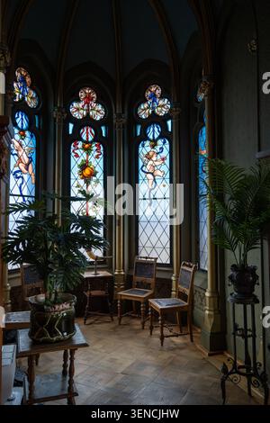 Königswinter, Deutschland - 22. Februar 25: Bucht-Fenster-Alkove mit Buntglaspaneelen, Stühlen und Pflanzen im Schloss Drachenburg, Königswinter, Nordrhein Stockfoto