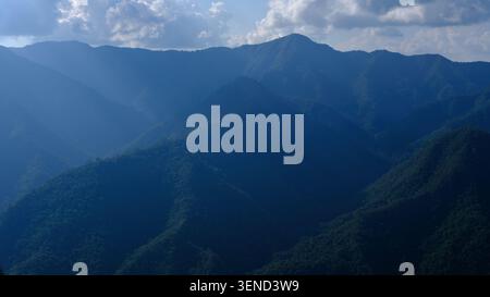 Ein Panoramablick auf mehrschichtige Bergkämme, bedeckt mit dichtem tropischem Regenwald unter einem trüben Himmel in südostasien, perfekt für Natur und Reisen. Stockfoto