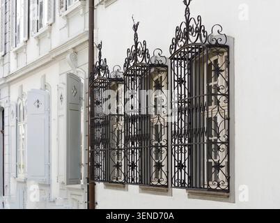 Verzierte schmiedeeiserne Fenstergitter an der historischen Fassade des weißen Gebäudes Stockfoto
