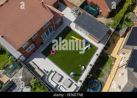 Blick aus der Vogelperspektive auf ein modernes Familienhaus mit Garten, Kunstrasen, Kinderspielgeräten und Sitzbereich im Freien in Wakefield West Yorksh Stockfoto