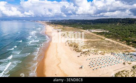 Costa Caparica, Lissabon. Blick aus der Vogelperspektive auf den Strand Costa Caparica, Portugal. Goldener Sand erstreckt sich entlang der Meereswellen. Grüne Dünen und Bäume Grenzen das Ufer. Stockfoto