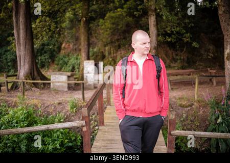 Mann, der über eine rustikale Holzbrücke in einer grünen Waldlandschaft spaziert und die Natur im Freien erkundet Stockfoto