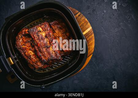 Moderne Küche – Zubereitung saftiger Spareribs mit Honigsauce in Airfryier, Grillfleisch Stockfoto