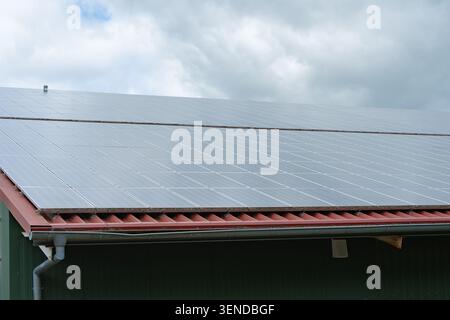 Eckige Nahaufnahme eines modernen Gebäudedachs mit Photovoltaik-Solarpaneelen. Repräsentiert umweltfreundliche Heimwerkersanierung und erneuerbare Energie Stockfoto