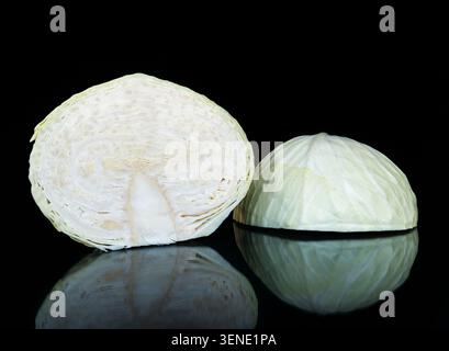 Zwei Hälften eines frischen Brassica oleracea-Kohls isoliert auf schwarzem Hintergrund, lebendiges grünes und weißes Gemüse mit Spiegelreflektion, professionell Stockfoto