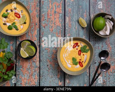 Eine Mischung aus cremiger Kürbissuppe mit asiatisch inspirierten Garnituren und rustikalem Design Stockfoto