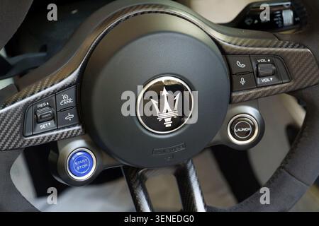 Nahaufnahme eines modernen Maserati Sportwagenlenkrads mit Karbonfaserverkleidung und dem legendären Trident-Logo Stockfoto