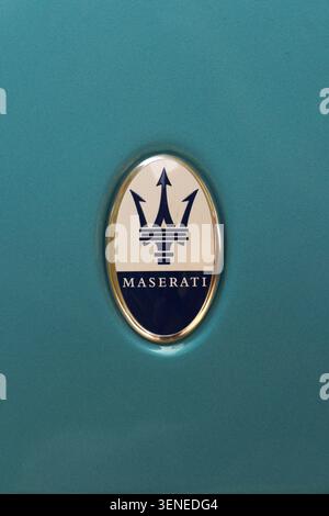Nahaufnahme des eleganten Maserati Trident-Emblems auf einer glänzenden, türkisfarbenen Fahrzeugkarosserie Stockfoto
