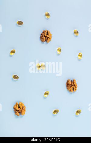 Omega-3 Fischöl Kapseln und Walnüsse verstreut blauer Hintergrund, repräsentiert gesunde Fette Gehirn Nahrungsergänzungsmittel. Neuropharmakologie, kognitive Gesundheit Stockfoto