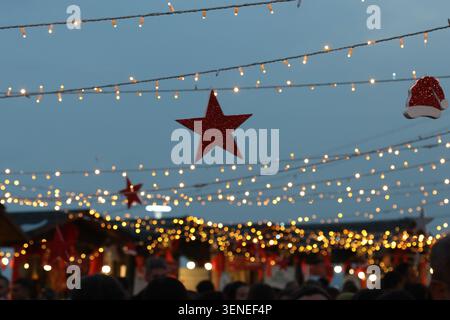 weihnachtslichter auf einem Charistmenmarkt mit verschwommenen Menschen Stockfoto