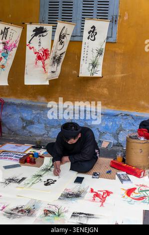 Ein vietnamesischer Schriftsteller/Künstler, der traditionelle Kalligraphie verwendet, indem er einen spitzen Stift verwendet, der mit schwarzer indischer Tinte beschichtet ist und verschiedene Strichbreiten durchzieht Stockfoto