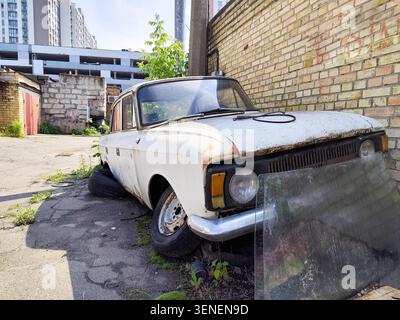 Wrack des alten weißen Autos mit kaputtem Glasfenster im Innenhof. Stockfoto