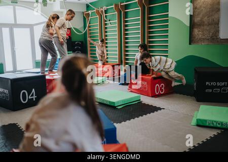 Kinder spielen und üben Gymnastik auf weichen Plyboxen in einem Indoor-Gymnastikkurs für Kinder Stockfoto