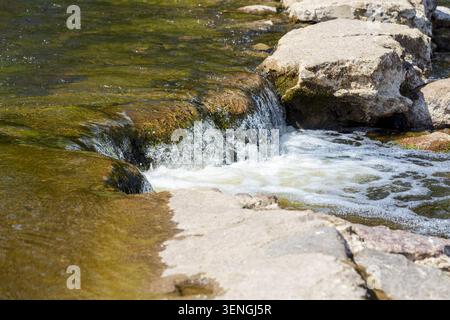 Schnell fließendes Flusswasser, das über natürliche Felsen und felsige Stromschnellen mit weißem Schaum rauscht, wunderschöne wilde Naturlandschaft. Stockfoto
