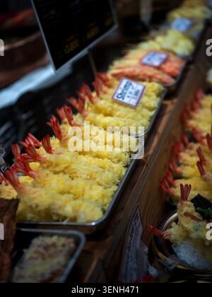 Reihen knuspriger, goldener Garnelentempura, die an einem japanischen Lebensmittelmarkt zum Verkauf angeboten werden. Stockfoto