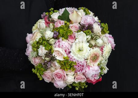 Runder Brautstrauß mit Gerbera, Pfingstrosen, Rosen und Calla-Lilie, rosa und weiß, schwarzer Hintergrund Stockfoto