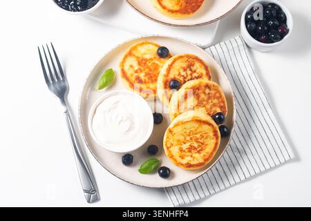 Traditionelle Hüttenkäsepfannkuchen mit Sauerrahm, Heidelbeermarmelade und frischen Beeren. Gesundes und eiweißes Frühstückskonzept. Stockfoto