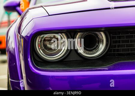 Leuchtend violette Luxuslimousine mit glänzender Lackierung, schwarzem Gehäusekontrast, runden Scheinwerfern mit weißer Verkleidung, dunklem Gitter- Stockfoto