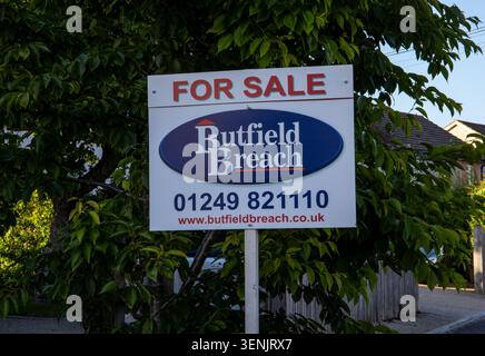 Ein Schild zum Verkauf von Immobilien von Butfield Breach Immobilienmaklern, die draußen vor Bäumen positioniert sind Stockfoto