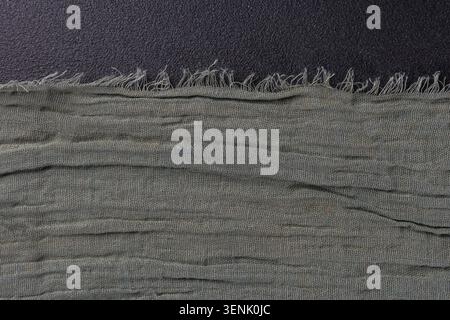 Horizontale Kante aus olivfarbenem Gewebe auf dunkler Textur Stockfoto