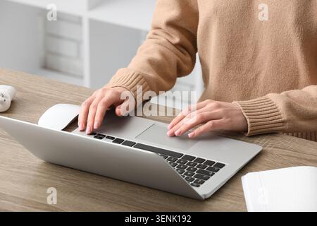 Frauen tippen mit den Händen auf der Laptop-Tastatur und verwenden das Trackpad für Fernarbeit oder Online-Lernen auf einem Holztisch – das wesentliche für digitale Produktivität und Moder Stockfoto