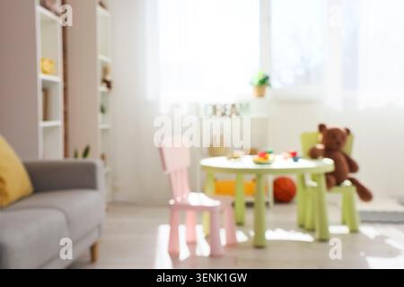 Unscharfer Hintergrund des hellen Kinderspielzimmers mit kleinem Tisch, Stühlen und Spielzeug für kreative Aktivitäten Stockfoto