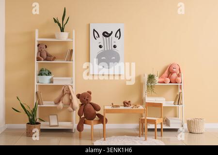 Spielzimmer für Kinder mit weißen Regalen, Holzmöbeln, Kuscheltieren und Zebra-Wandbildern Stockfoto