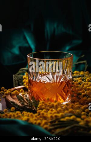 Whiskey mit Eis in Kristallglas mit Mimosa Flowers Spring Alcohol Konzept Stockfoto