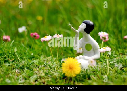 Antike Porzellanfigur „Löwenzahn“ aus der UdSSR-Zeit auf einem grünen Naturfeldgrund mit Blumen. Nahaufnahme der Vorderansicht. Hergestellt in Lettland. Stockfoto