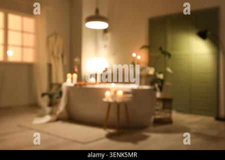 Entspanntes Badezimmer mit Badewanne und beleuchteten Kerzen, gemütlichem Spa-Erlebnis zu Hause, verschwommenem Hintergrund für Ruhe Stockfoto